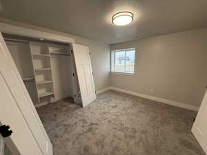 Unfurnished bedroom featuring a closet, carpet floors, and a textured ceiling