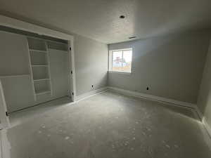 Unfurnished bedroom featuring a textured ceiling and a closet