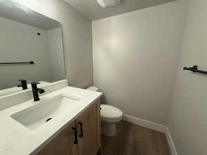 Bathroom with hardwood / wood-style flooring, vanity, a textured ceiling, and toilet