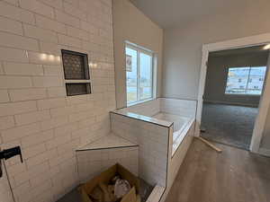 Bathroom with tiled bath and hardwood / wood-style floors