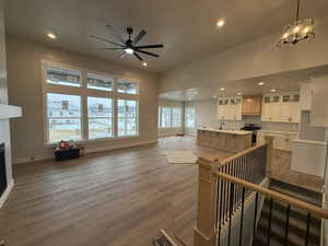 Living room featuring ceiling fan with notable chandelier, wood-type flooring, and sink