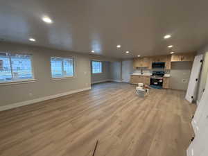 Unfurnished living room featuring sink and light hardwood / wood-style flooring