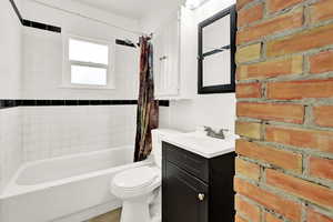 Full bathroom with vanity, shower / bath combination with curtain, and toilet