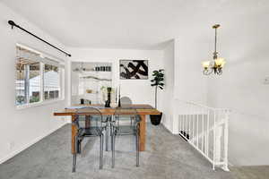 Carpeted dining room featuring a textured ceiling and an inviting chandelier