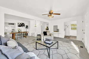 Living room featuring ceiling fan with notable chandelier