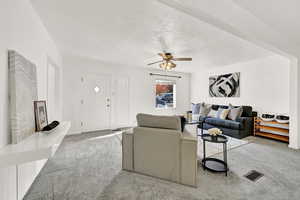 Carpeted living room with a textured ceiling and ceiling fan