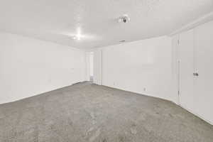 Empty room with carpet floors and a textured ceiling