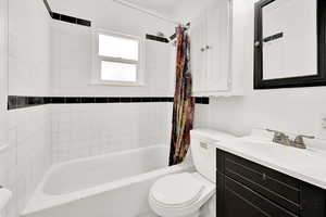 Full bathroom with shower / bath combo, vanity, and toilet