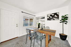 Carpeted dining area featuring a textured ceiling