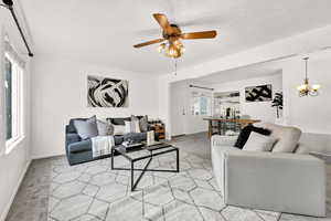 Carpeted living room with ceiling fan with notable chandelier