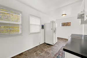 Kitchen featuring white fridge with ice dispenser and white cabinets