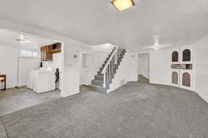 Unfurnished living room featuring light carpet, independent washer and dryer, and a textured ceiling