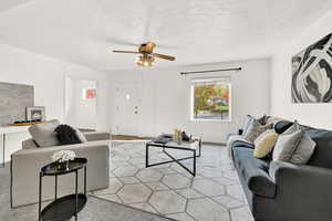 Living room featuring light carpet, a textured ceiling, and ceiling fan