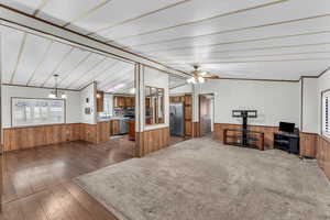 Living room with a textured ceiling, ceiling fan with notable chandelier, dark hardwood / wood-style floors, and wood walls