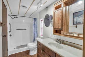 Bathroom with walk in shower, toilet, vanity, and hardwood / wood-style flooring