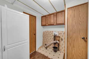 Clothes washing area with a textured ceiling, cabinets, dark wood-type flooring, and hookup for a washing machine