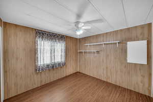 Spare room featuring hardwood / wood-style flooring, ceiling fan, a textured ceiling, and wooden walls