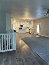 Kitchen featuring white cabinets, appliances with stainless steel finishes, hanging light fixtures, and hardwood / wood-style floors