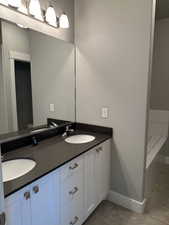 Bathroom featuring tile patterned floors, vanity, toilet, and a tub