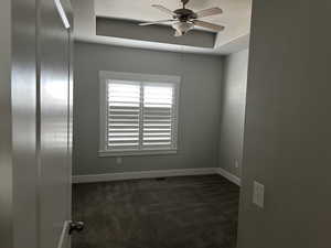 Unfurnished room featuring dark carpet and ceiling fan