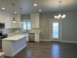 Kitchen featuring plenty of natural light, a kitchen island, dark hardwood / wood-style flooring, and appliances with stainless steel finishes