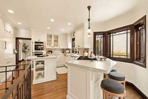 Kitchen featuring appliances with stainless steel finishes, light stone counters, sink, a center island, and hanging light fixtures