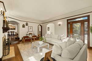 Living room with a chandelier, dark wood-type flooring, and ornamental molding