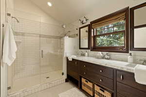 Bathroom featuring tile patterned floors, vanity, vaulted ceiling, and an enclosed shower