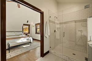 Bathroom with hardwood / wood-style flooring, a shower with shower door, and lofted ceiling