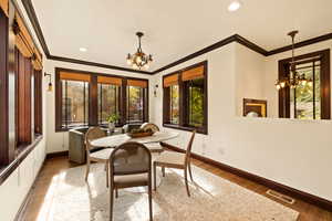 Dining room with dark hardwood / wood-style flooring, an inviting chandelier, and ornamental molding