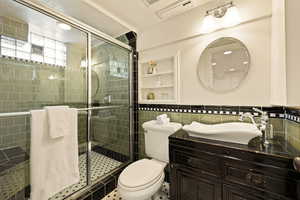 Bathroom with tile patterned flooring, an enclosed shower, toilet, vanity, and tile walls