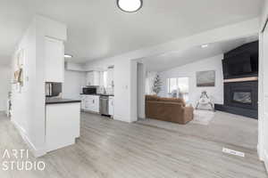 Kitchen featuring dishwasher, light hardwood / wood-style flooring, white cabinetry, and lofted ceiling