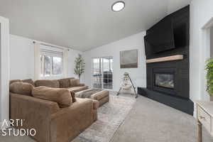 Living room featuring a large fireplace, lofted ceiling, and light carpet