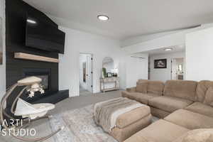 Carpeted living room featuring a large fireplace and vaulted ceiling