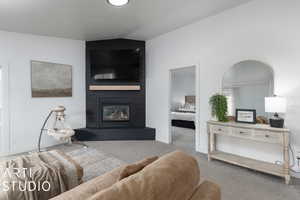 Living room featuring light carpet, a fireplace, and vaulted ceiling