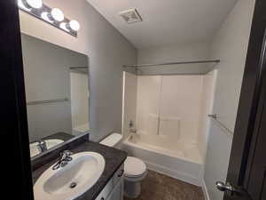 Full bathroom with bathing tub / shower combination, linoleum patterned floors, a textured ceiling, toilet, and vanity