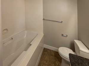 Ensuite bathroom featuring linoleum patterned flooring, a bathing tub, and toilet