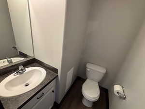 Half Bathroom featuring Linoleum/ wood-style flooring, vanity, and toilet