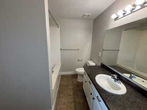 Primary suite bathroom featuring a textured ceiling, vanity, toilet, and a bathtub