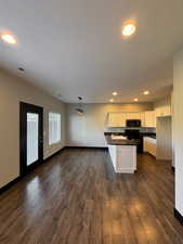 Kitchen featuring white cabinets, black range with electric cooktop, dark linoleum / wood-style flooring, and decorative light fixtures