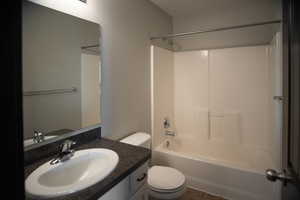 Full bathroom featuring linoleum patterned flooring, vanity, shower combination, and toilet