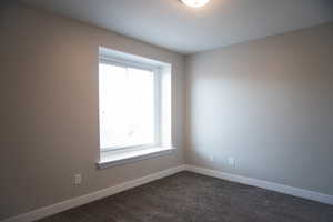 Spare bedroom featuring plenty of natural light and dark carpet