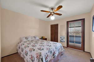 Bedroom with a closet, light colored carpet, and ceiling fan