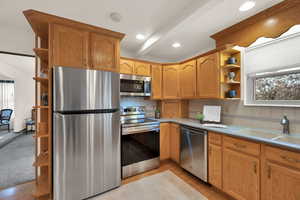 Kitchen featuring beam ceiling, sink, appliances with stainless steel finishes, and tasteful backsplash