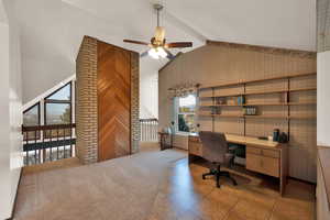 Home office in open loft area with beamed ceiling, built in desk, high vaulted ceiling, and ceiling fan