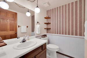 Bathroom with tile patterned flooring, vanity, toilet, and tile walls