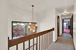 Hallway over looking the entry, featuring a chandelier, and a wealth of natural light