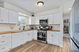 Kitchen featuring appliances with stainless steel finishes, white cabinetry, and butcher block counters