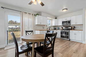 Kitchen with white cabinets, light hardwood / wood-style floors, and appliances with stainless steel finishes