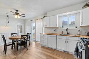 Kitchen with white cabinets, dishwasher, sink, and wooden counters